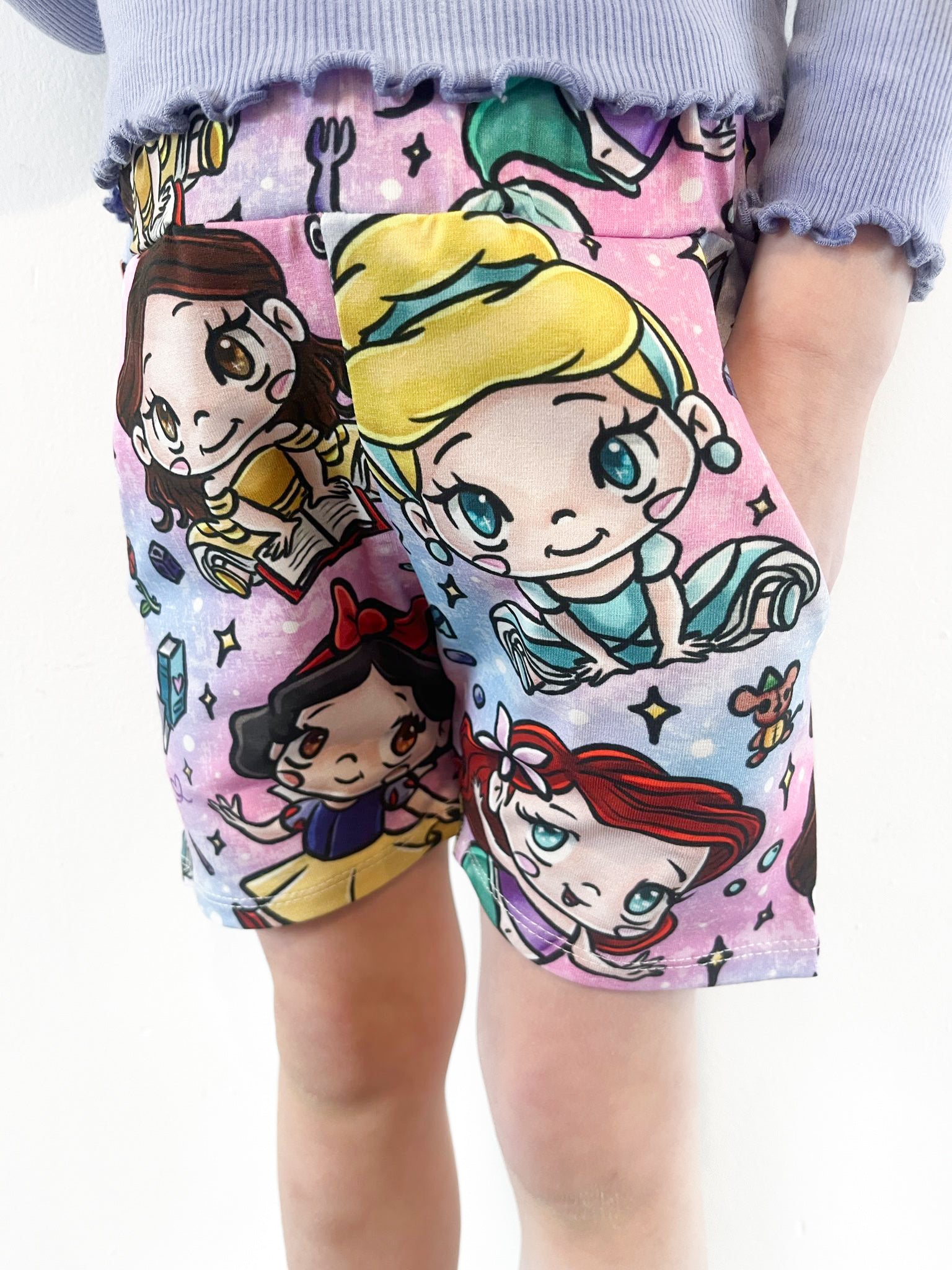 Child wearing pastel jogger shorts with kawaii princess characters, stars and magical background