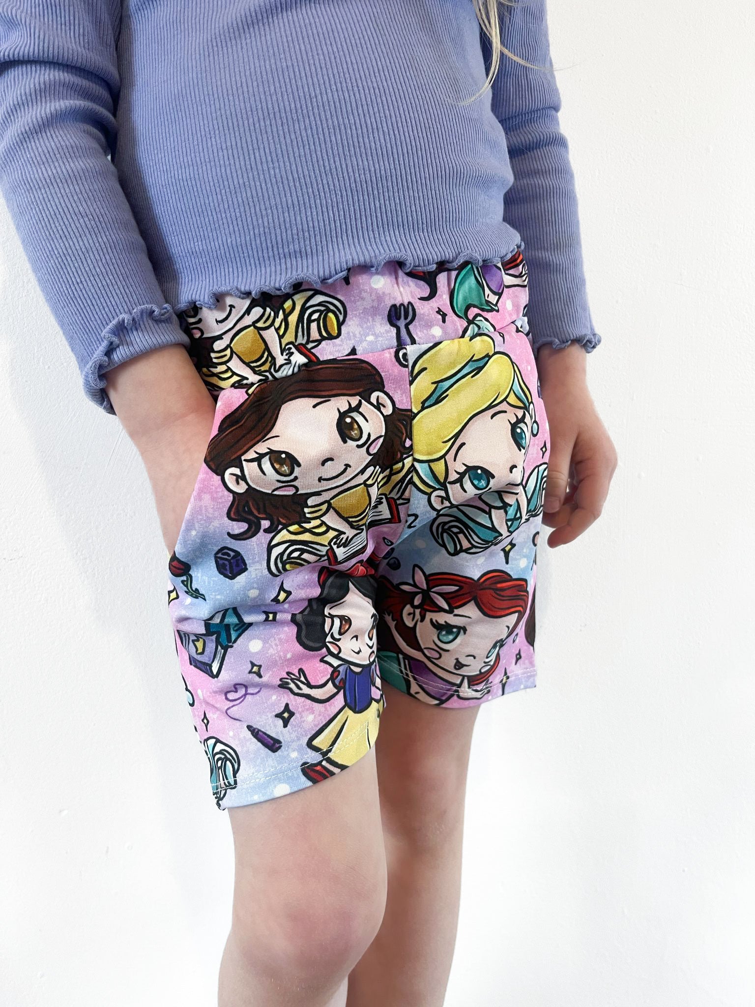 Child wearing pastel jogger shorts with kawaii princess characters, stars and magical background