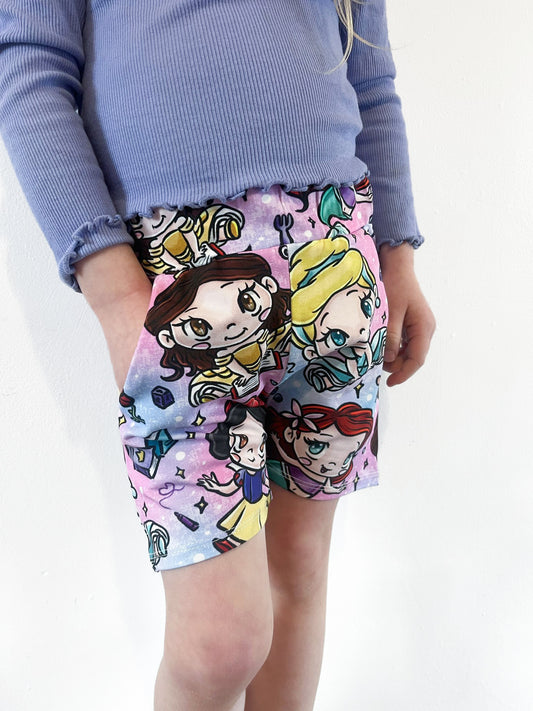 Child wearing pastel jogger shorts with kawaii princess characters, stars and magical background